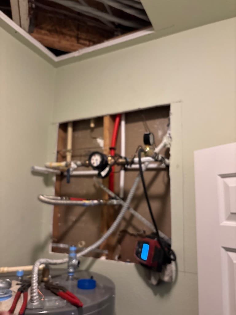 Opened wall with in-progress CPVC to PEX routing and testing setup