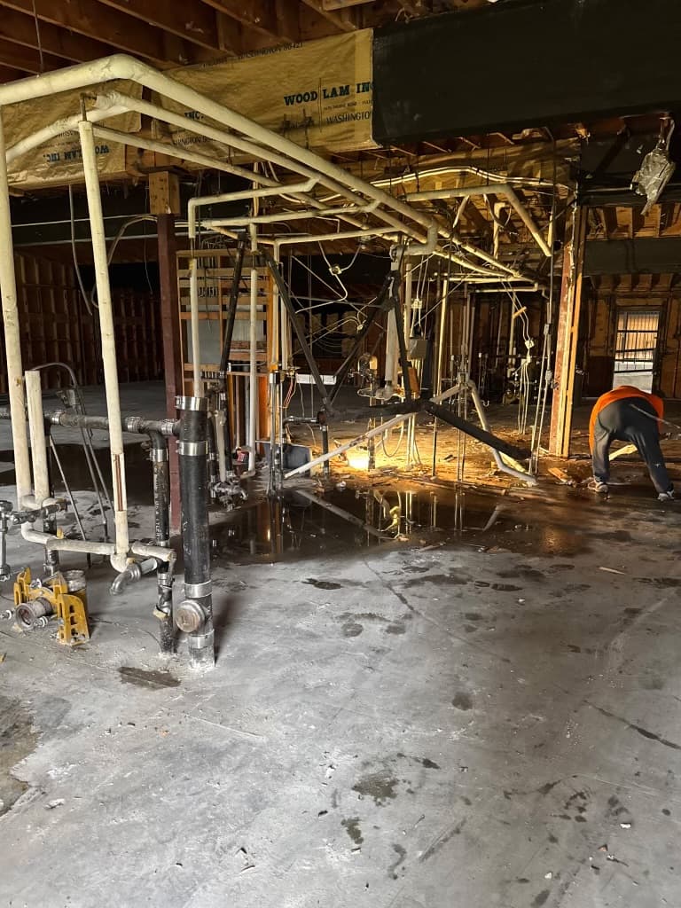 Commercial interior demolition area with exposed piping and plumbing access points during repipe preparation