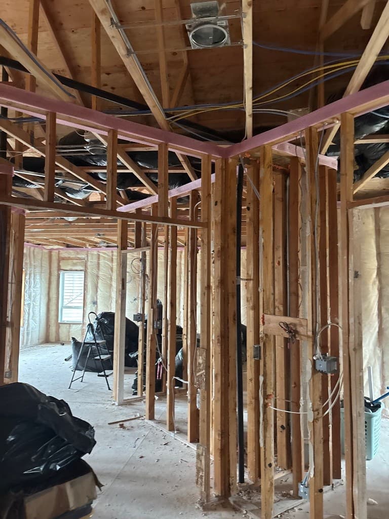 Open framed interior showing active plumbing and vent routing in restoration phase