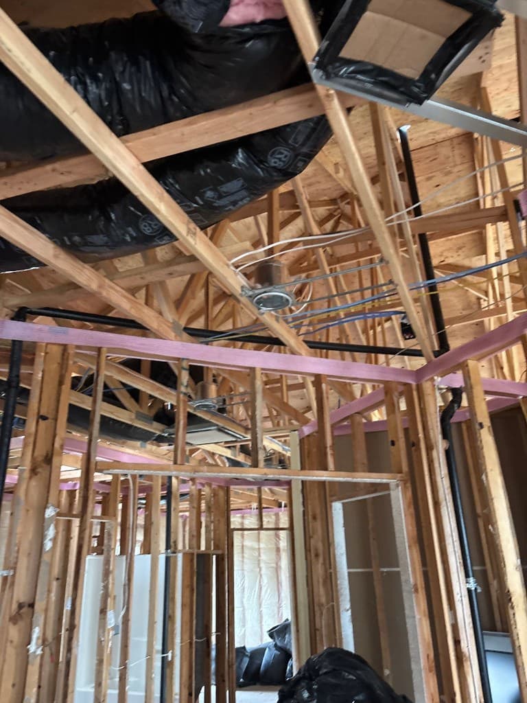 Ceiling and wall framing with coordinated plumbing and vent rough-in in progress