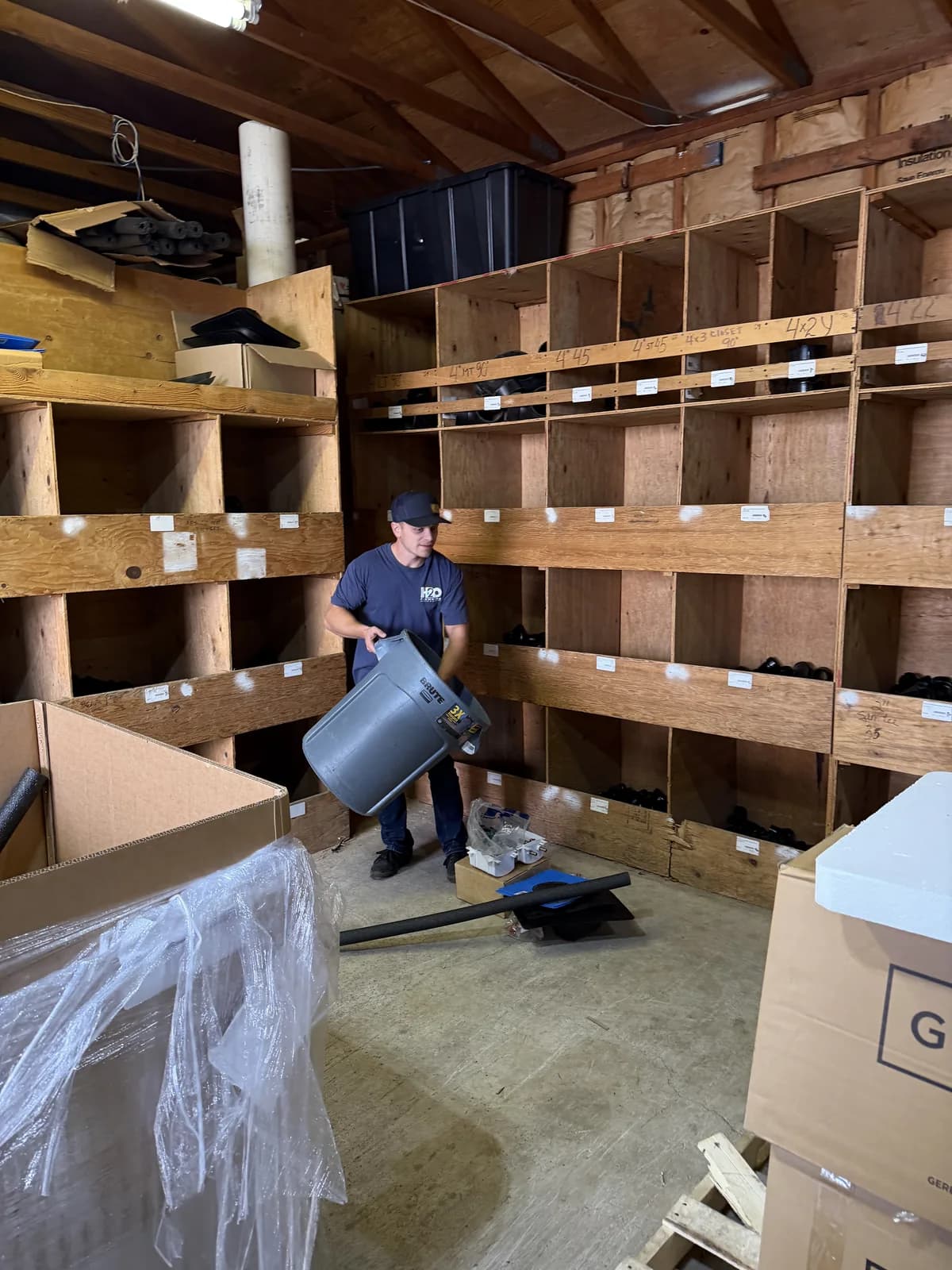 H2O crew member carrying a bin in the shop supply room
