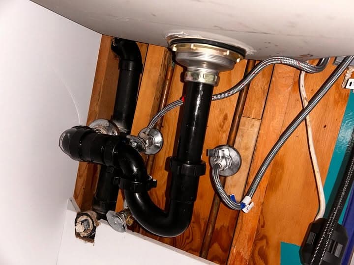 Plumber repairing a leaking under-sink drain in Vancouver WA